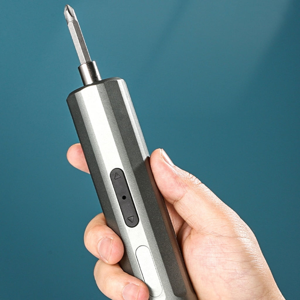 Hand hält einen grauen und silbernen Elektroschrauber vor blauem Hintergrund. Der Schraubendreher hat eine Spitze aus Metall.