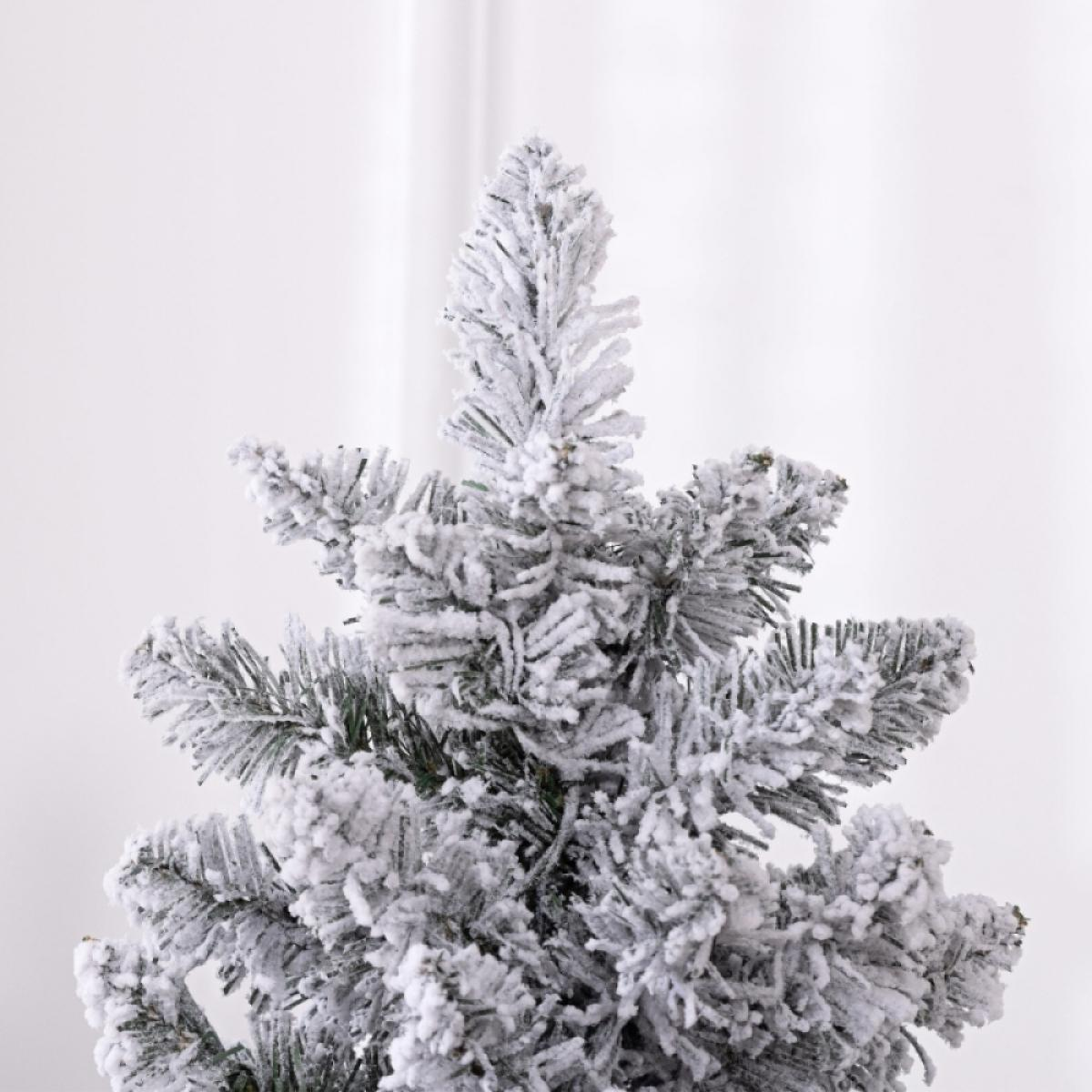 Nahaufnahme eines schneebedeckten Weihnachtsbaums. Weißer Schnee bedeckt die grünen Nadeln. Der Hintergrund ist ein weißer Vorhang.
