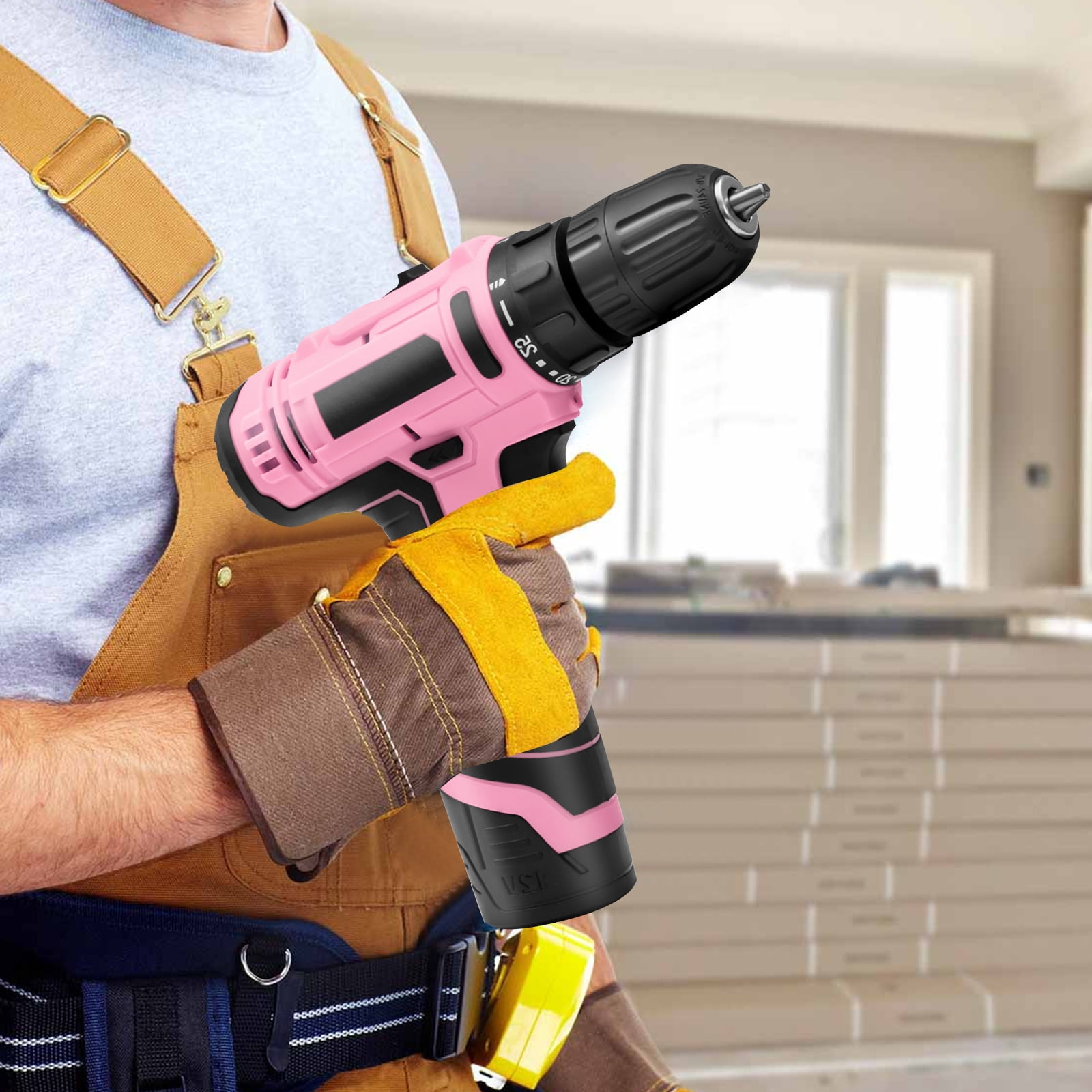 Eine Person hält einen rosa-schwarzen Bohrer. Sie trägt Arbeitskleidung und Handschuhe. Ein gelbes Werkzeug hängt an ihrem Gürtel.