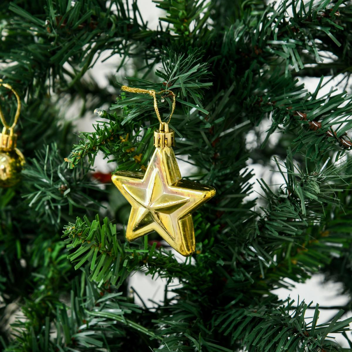 Ein goldener Sternschmuck hängt an einem grünen Weihnachtsbaum, mit einem goldenen Kugelschmuck im Hintergrund.