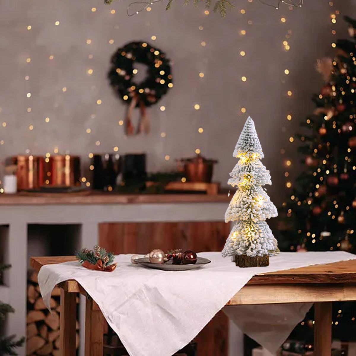 Ein dekorierter Weihnachtsbaum auf einem Tisch mit Lichtern und Ornamenten. Ein Weihnachtsbaum ist im Hintergrund.