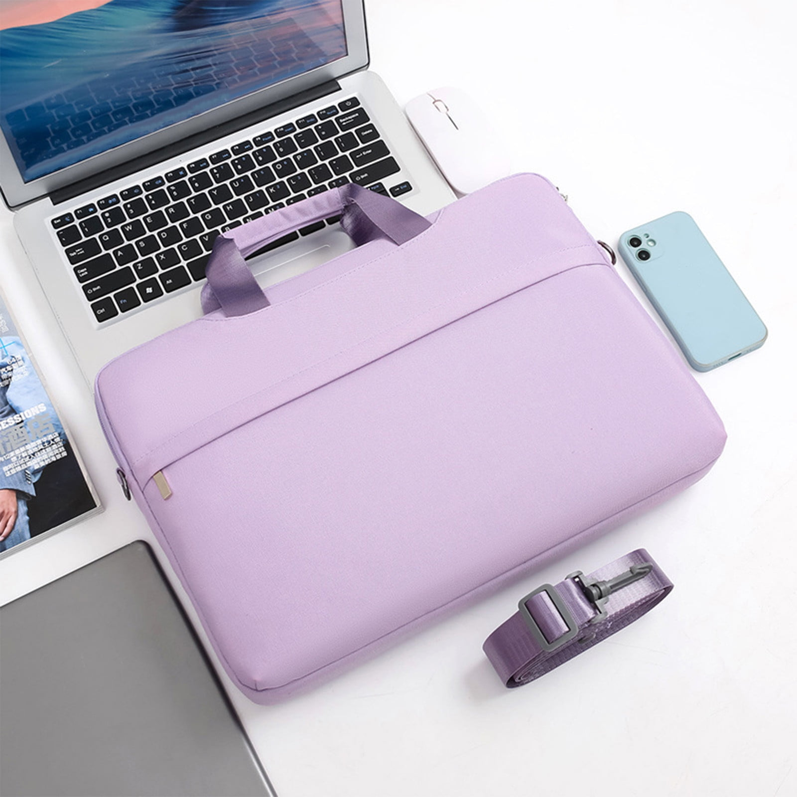 Ein Laptop, eine lila Laptoptasche, ein blaues Telefon, eine weiße Maus und ein Riemen auf einer weißen Oberfläche.