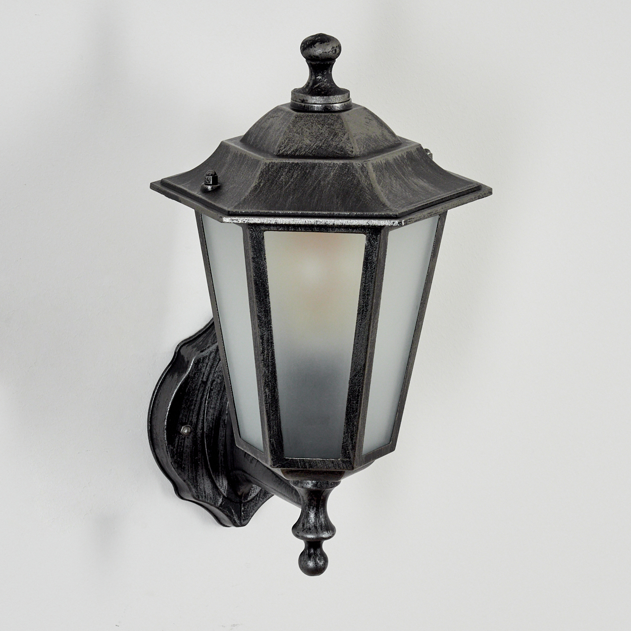 Eine dekorative Außenlampe, schwarz mit Milchglasscheiben, ist an einer weißen Wand befestigt. Die Lampe hat ein klassisches Design.