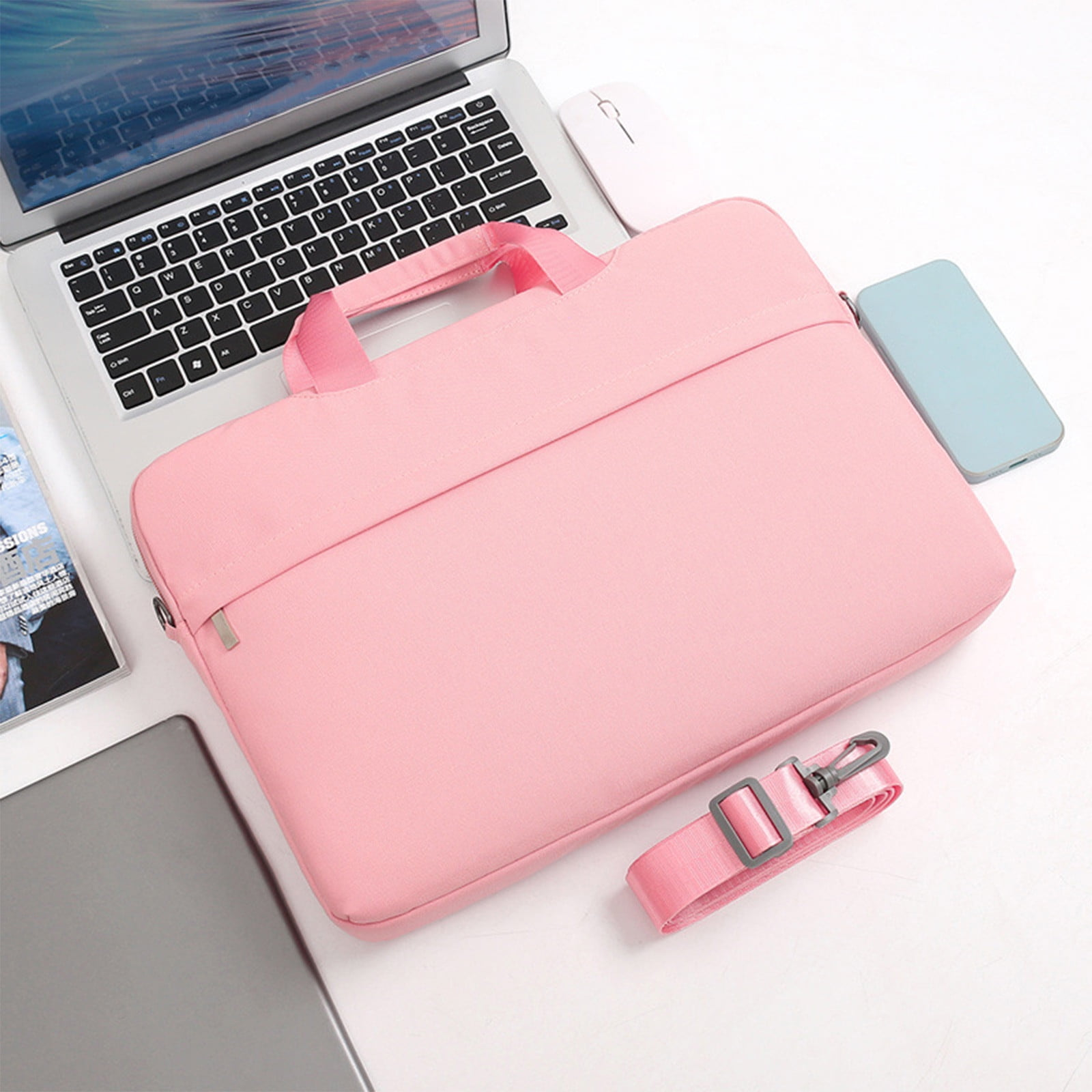 Rosa Laptoptasche mit Griff, Riemen und Laptop. Maus und Telefon liegen neben der Tasche auf weißer Oberfläche.