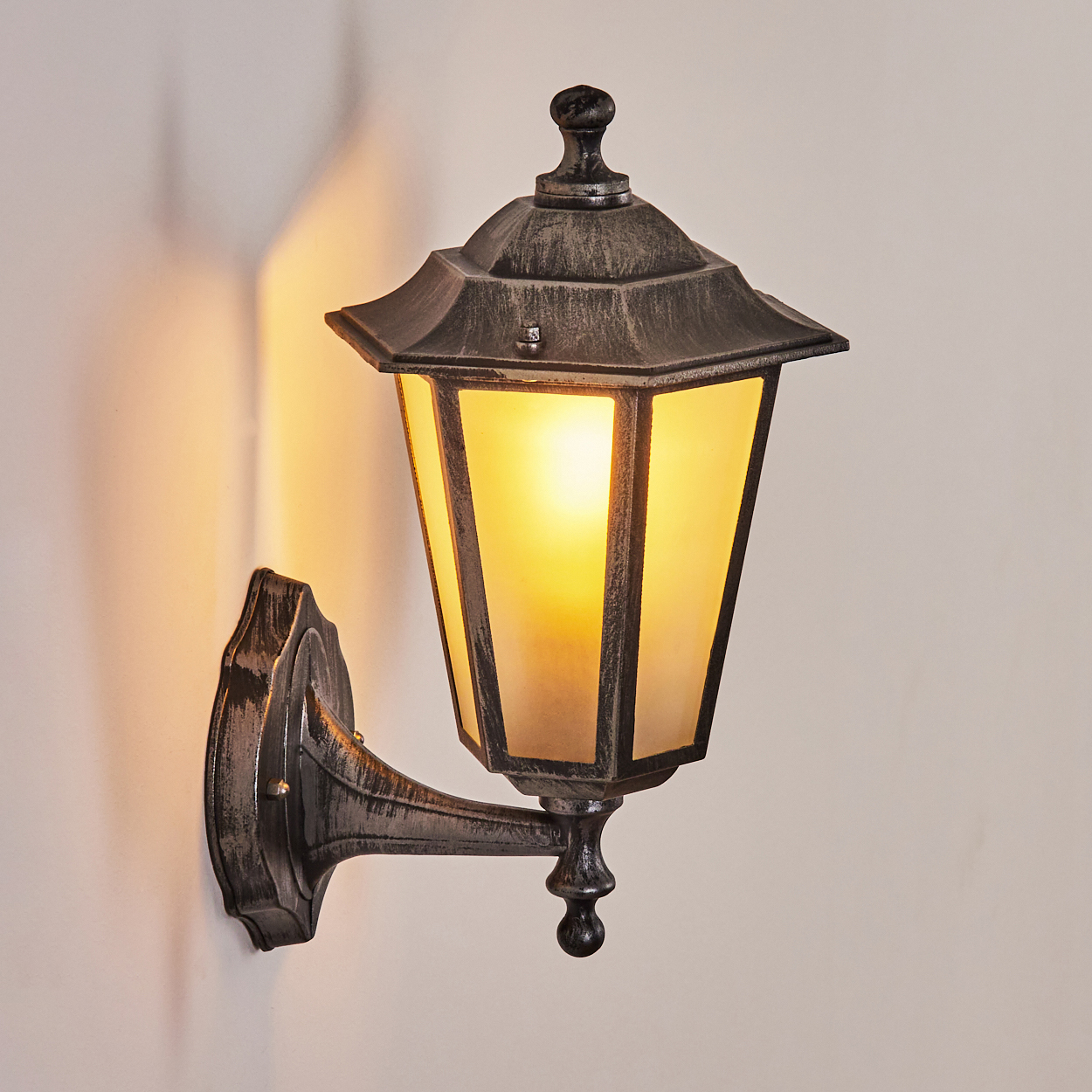 Eine dekorative Außenwandleuchte mit warmem Licht, montiert an einer cremefarbenen Wand.