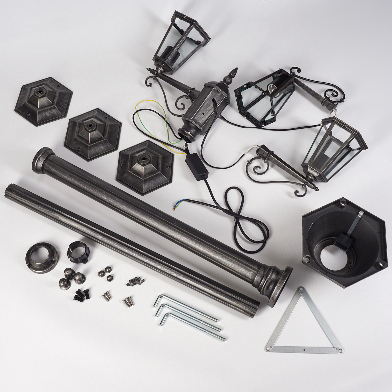 Zerlegte Teile einer Außenlampe auf weißem Grund. Enthält Lampenköpfe, Stangen, Sockel, Schrauben und Werkzeuge. Silber- und Schwarzfarben.