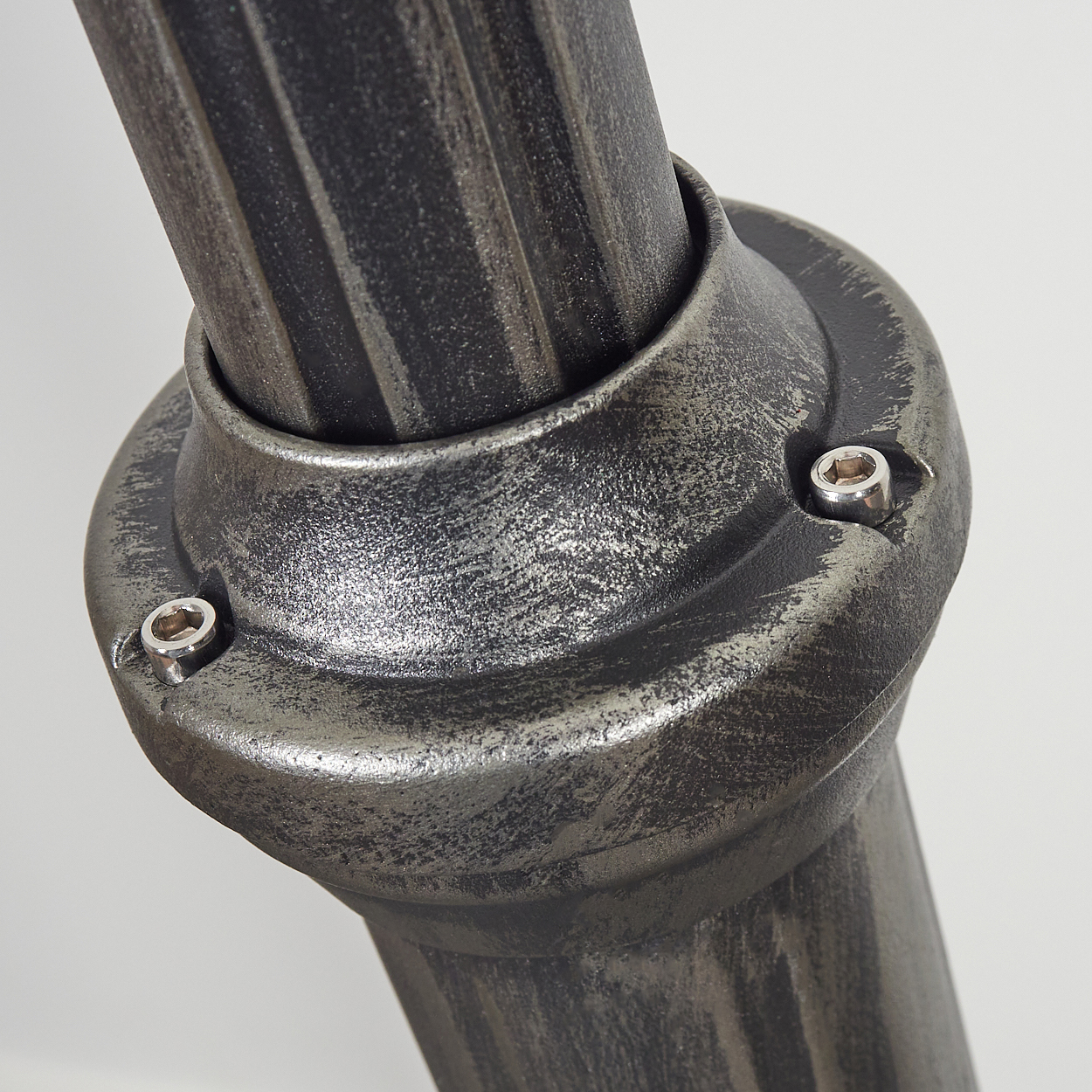 Nahaufnahme einer Metallkonstruktion mit strukturierter, silbergrauer Oberfläche. Zwei Sechskantschrauben sichern eine Verbindung.