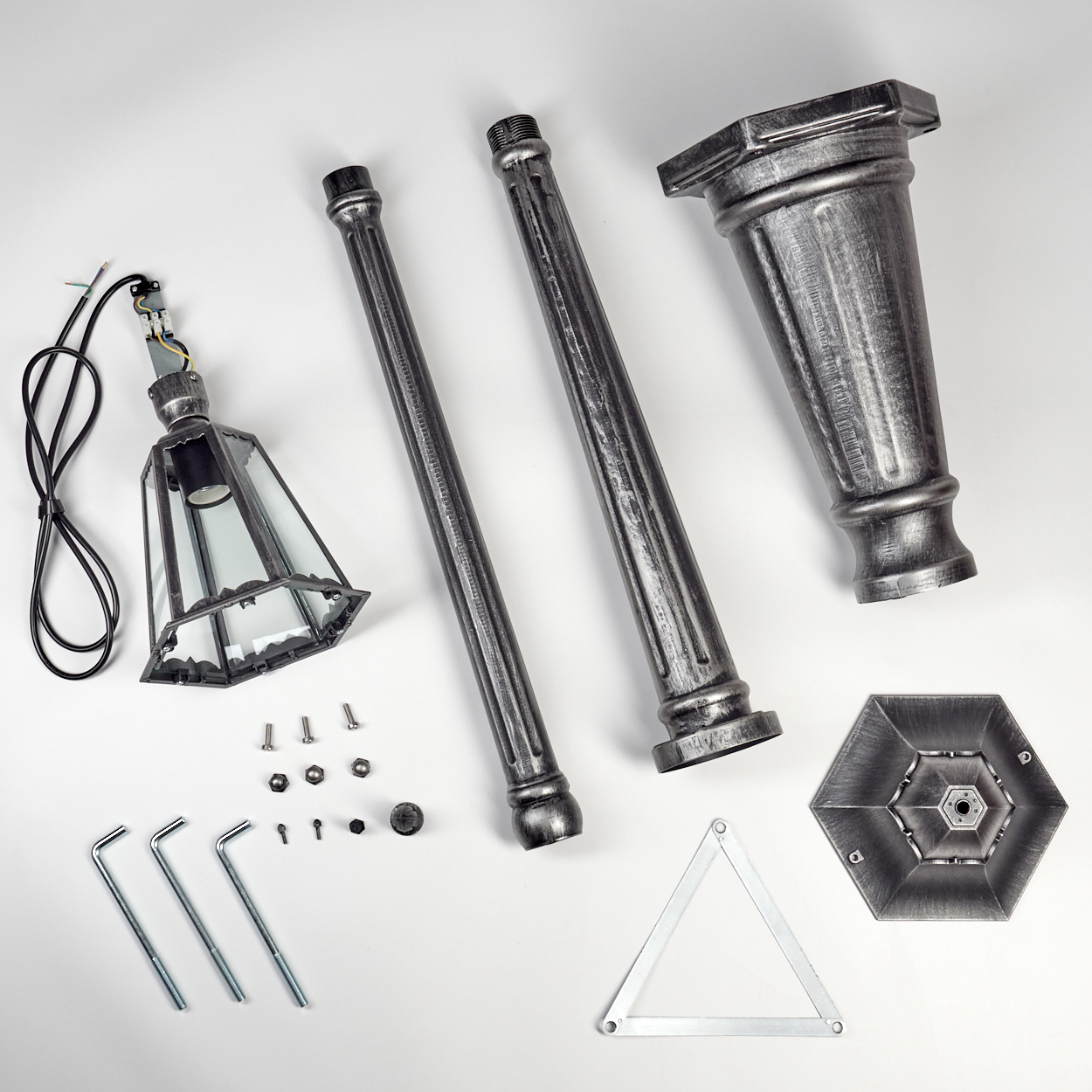 Zerlegte Lampenteile auf weißem Hintergrund: Pfostenabschnitte, Lampenkopf, Sockel, Hardware und Werkzeuge. Metallisch graue Farbe.
