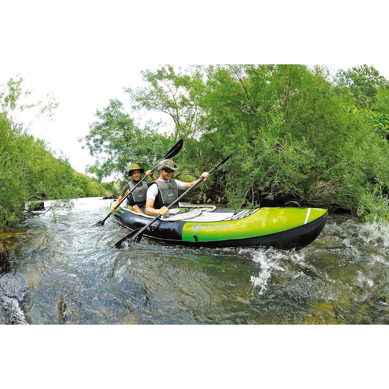 Zwei Personen paddeln mit einem grün-schwarzen Kajak auf einem Fluss, umgeben von üppigen grünen Bäumen.