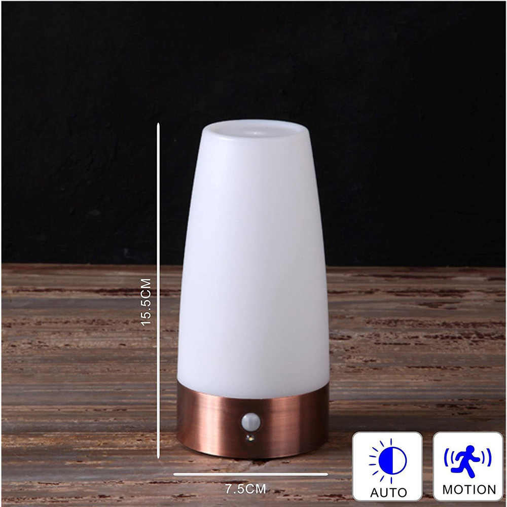 Eine weiß-kupferfarbene Lampe steht auf einer Holzoberfläche. Sie hat einen Bewegungssensor und Automatikmodus. Dunkler Hintergrund.
