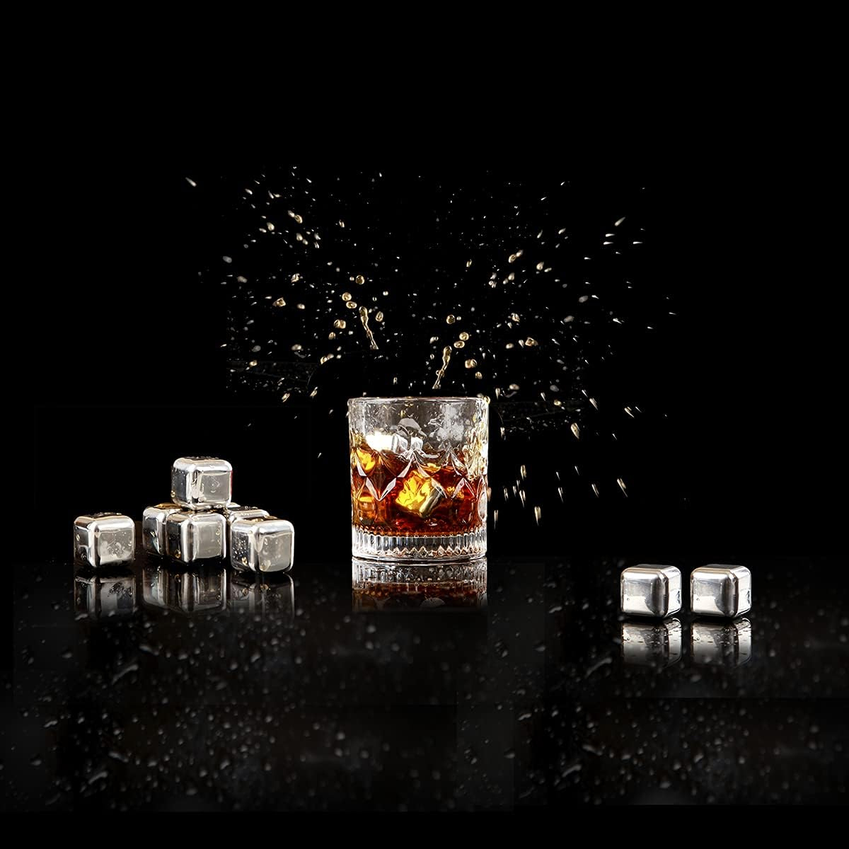 Ein Glas mit Whisky und Eiswürfeln, Spritzeffekt. Metallische Eiswürfel verstreut. Schwarzer Hintergrund mit Wassertropfen.