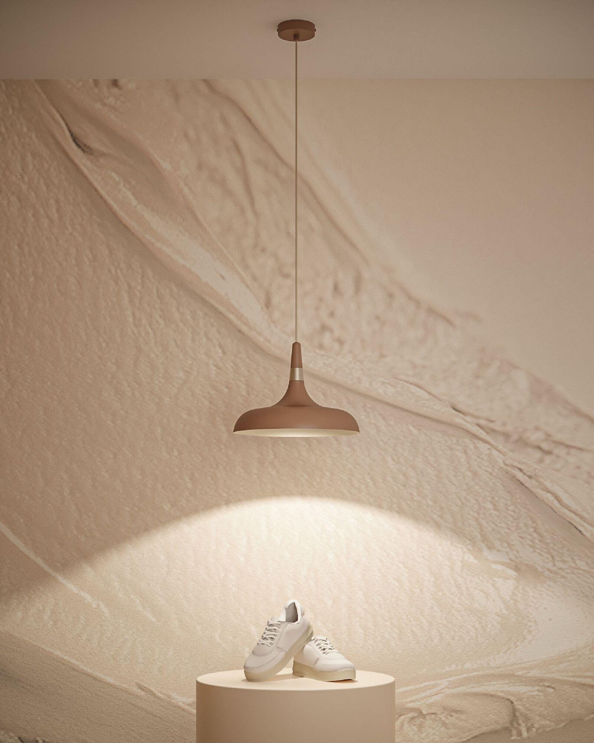Eine braune Pendelleuchte beleuchtet weiße Turnschuhe auf einem beigen Sockel vor einer beigen strukturierten Wand.