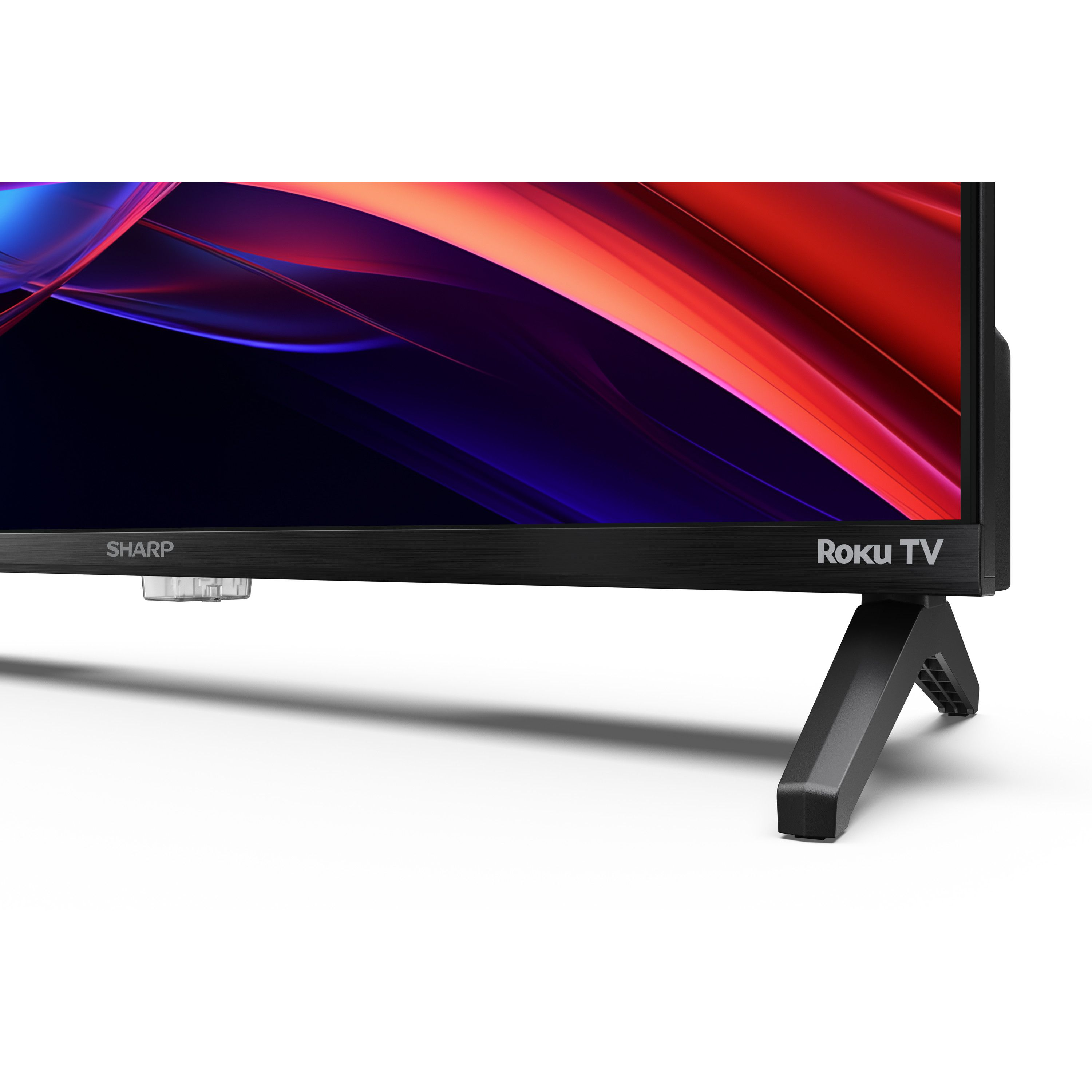 Ein Sharp Roku TV auf weißer Oberfläche mit farbenfroher abstrakter Anzeige. Der Fernseher ist schwarz, mit schwarzen Beinen.