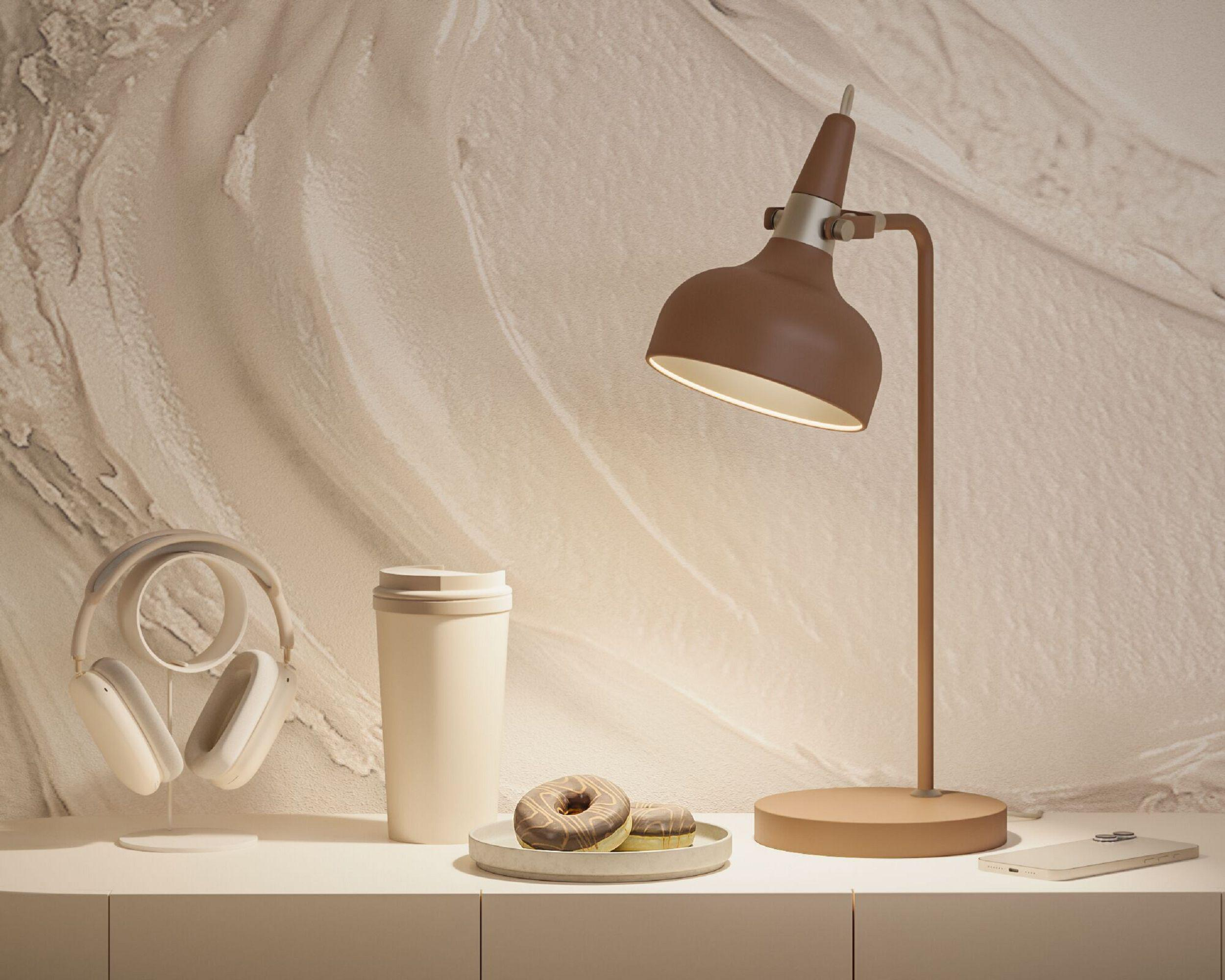 Biurko z lampą, słuchawkami, kubkiem, pączkami i telefonem. Schemat kolorów beżowy i brązowy.