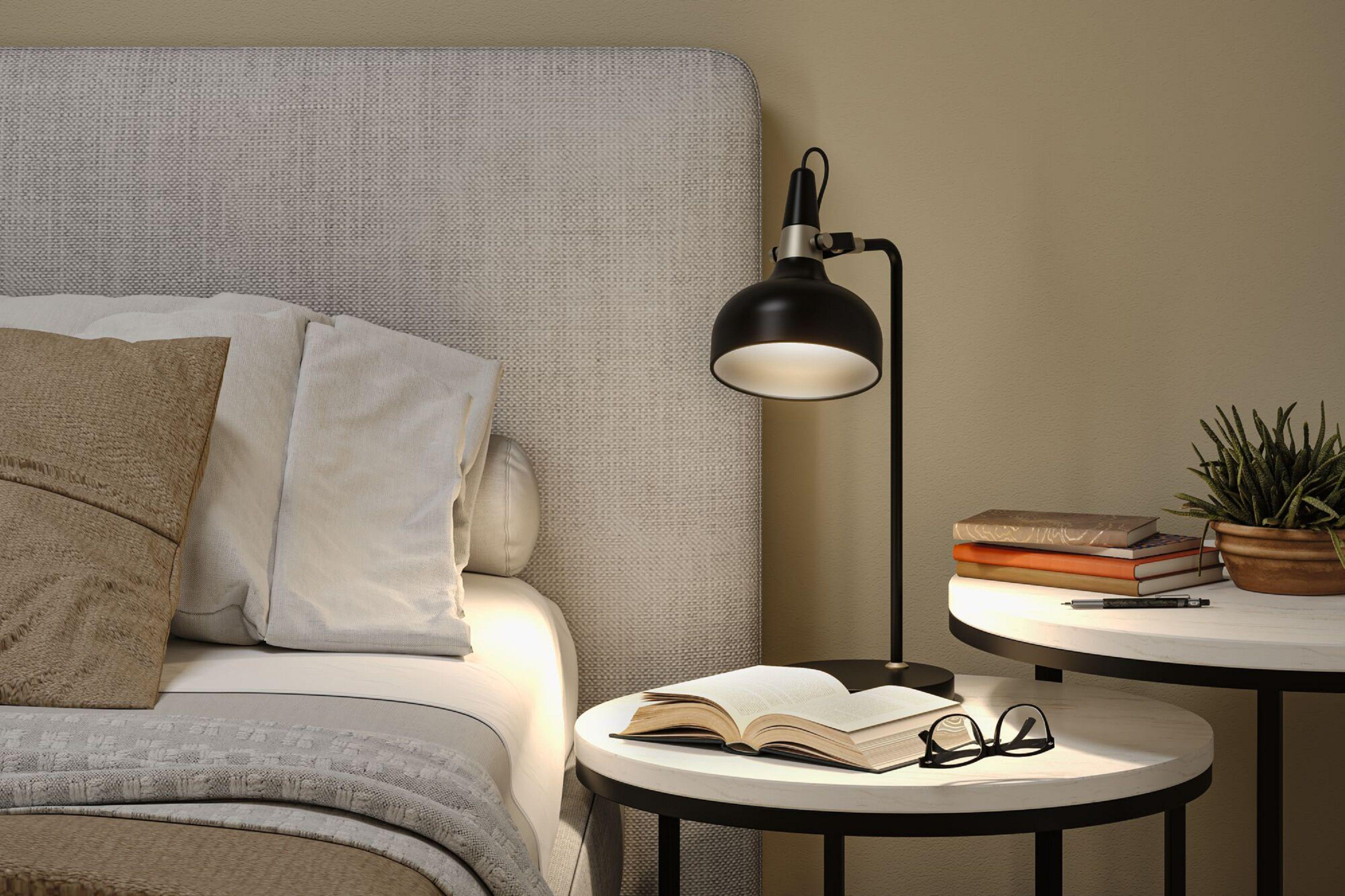 Scena sypialni z łóżkiem, lampą, książkami i okularami na stoliku nocnym. Łóżko ma poduszki i koc.