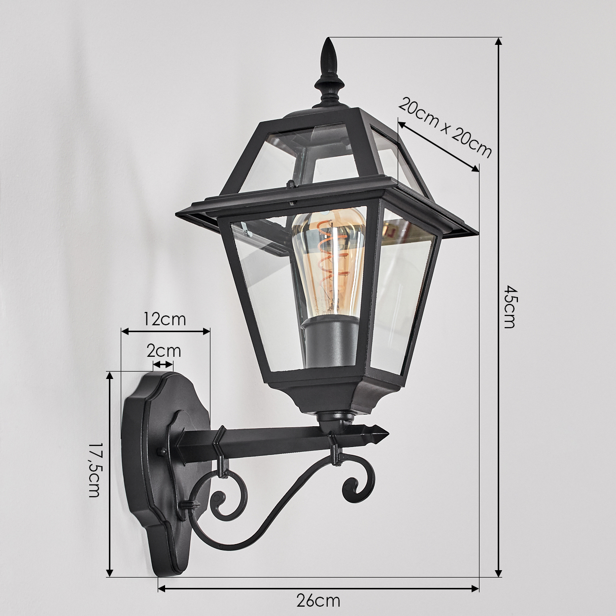 Schwarze Außenlaterne mit Glasscheiben, Maße angegeben. Mit Edison-Glühbirne und verziertem Halter an einer weißen Wand.
