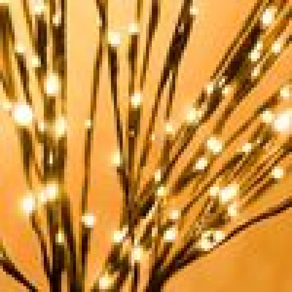 Nahaufnahme von künstlichen Zweigen mit kleinen, warmweißen Lichtern vor weichem orangefarbenem Hintergrund. Die Zweige sind dunkelbraun.