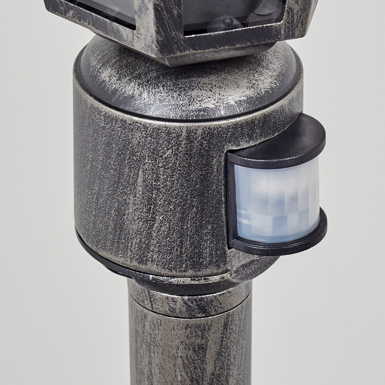 Nahaufnahme einer metallischen Laterne mit Bewegungssensor. Die Stange ist grau mit schwarzen Akzenten. Der Sensor ist ein Rechteck.