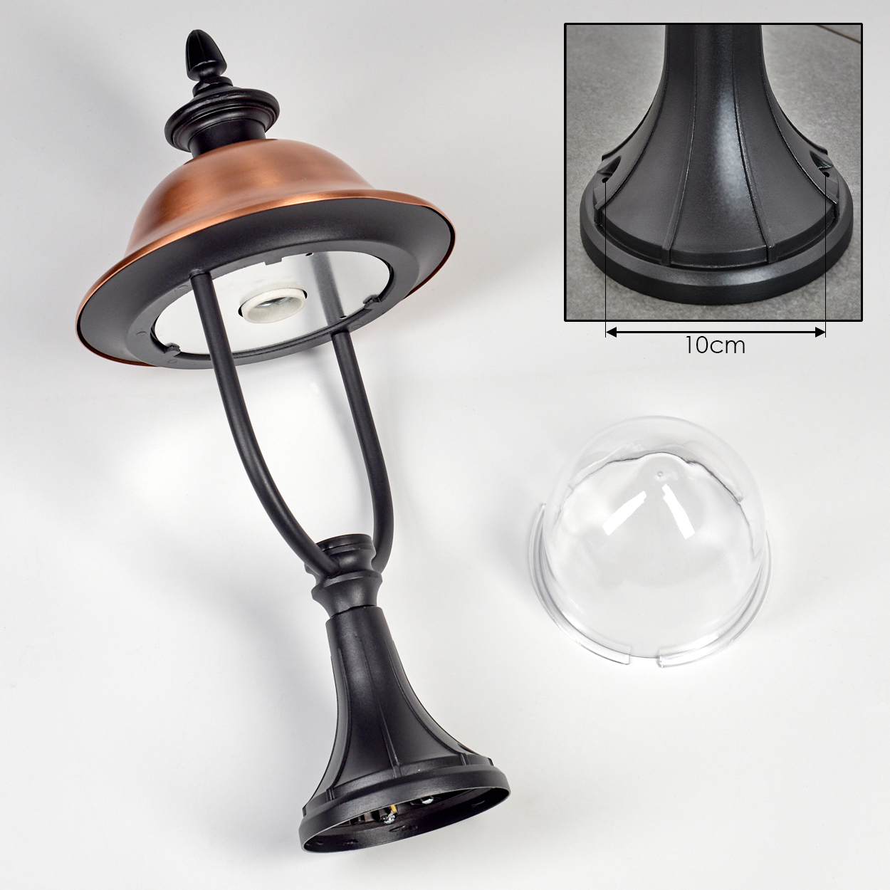 Eine zerlegte schwarze und kupferfarbene Außenlampe mit klarer Kuppelabdeckung und einem 10 cm großen Basisdetail auf weißer Oberfläche.