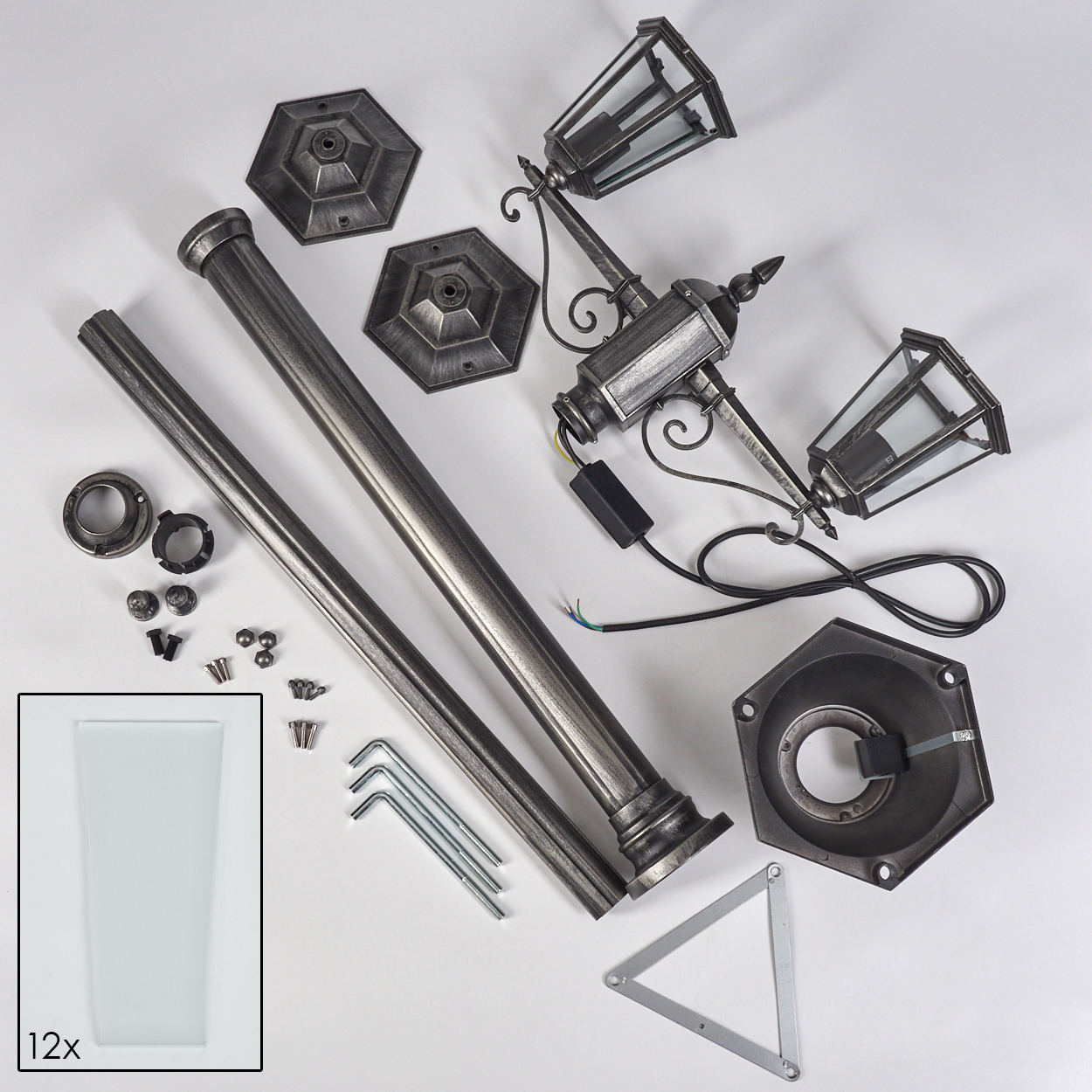 Zerlegter Außenlampenbausatz. Enthält Pfosten, Sockel, Lampenköpfe, Schrauben und Glasscheiben auf weißem Untergrund.