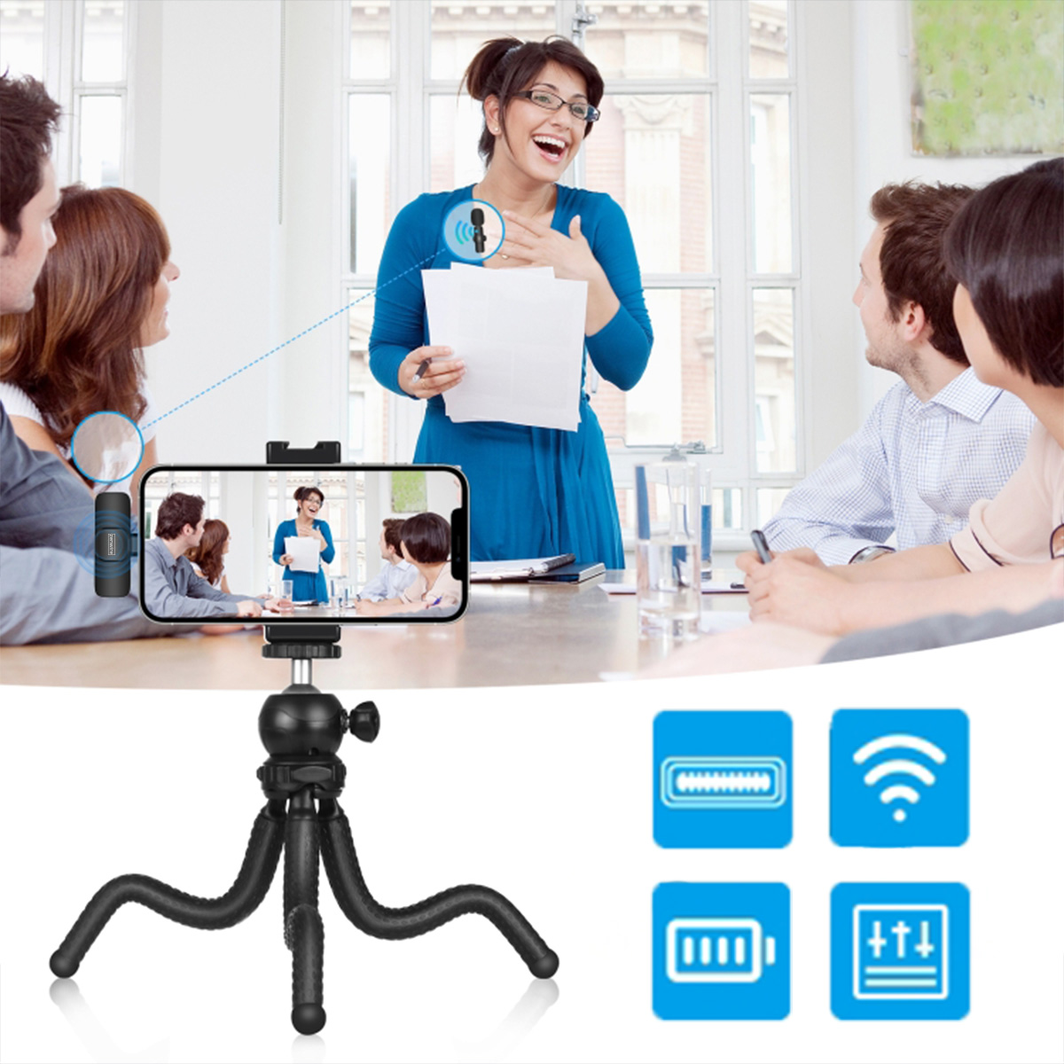 Kobieta w niebieskim prezentuje grupie. Telefon na statywie wyświetla scenę. Ikony baterii i sygnałów bezprzewodowych.