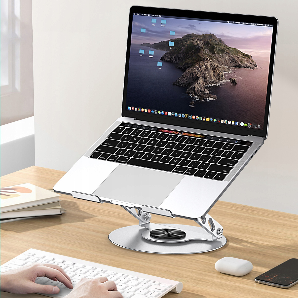 Laptop na stojaku wyświetla krajobraz górski. Klawiatura i mysz są na pierwszym planie, z telefonem na biurku.