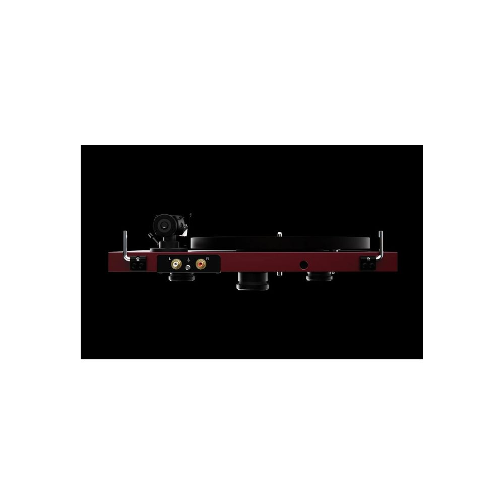 Czerwony gramofon na czarnym tle. Ma czarny talerz i ramię. Widoczne srebrne złącza.