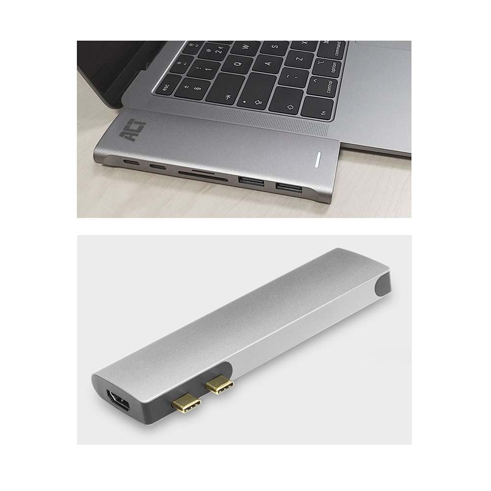 Un hub USB argentato collegato a un laptop. L'hub ha più porte, tra cui USB, ed è posizionato su una superficie di legno.
