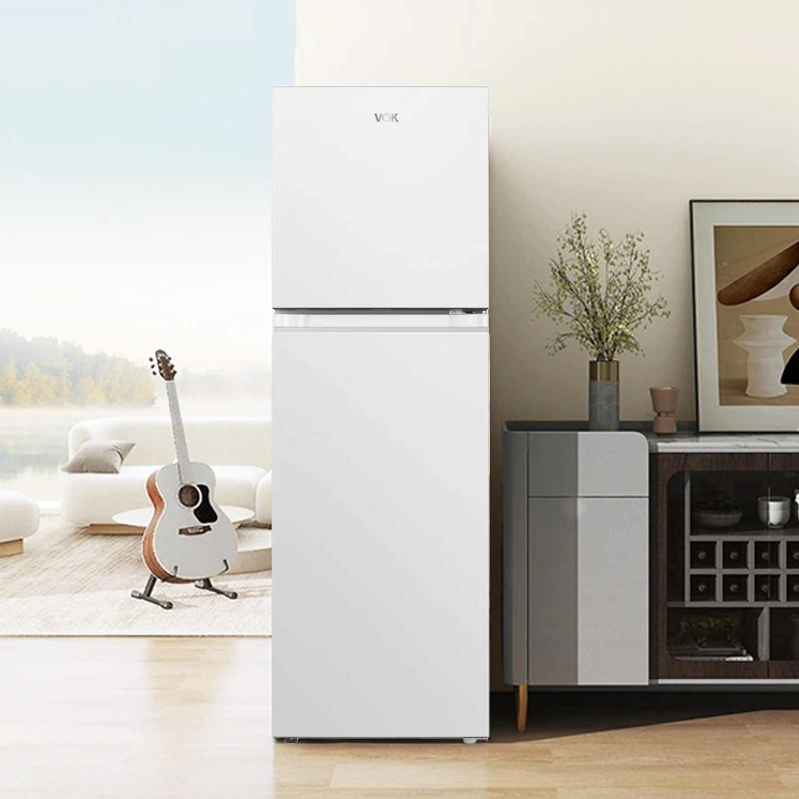 Un refrigerador blanco en una habitación. Una guitarra frente a un sofá. Un gabinete con decoración a la derecha.
