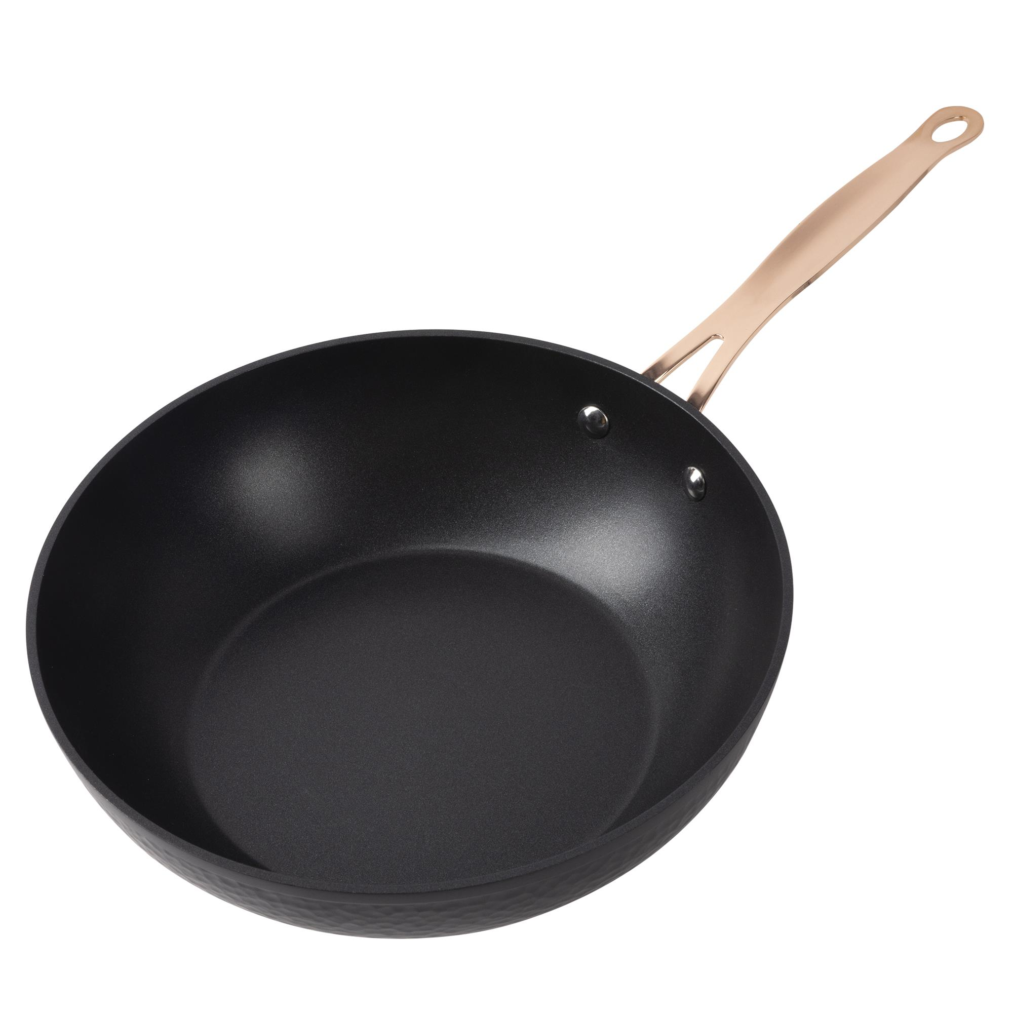 Una sartén negra con mango color cobre. La sartén está sobre un fondo blanco.