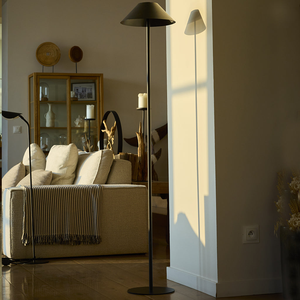 Ein modernes Wohnzimmer mit Sofa, Lampen und Dekorationsgegenständen. Der Raum ist gut beleuchtet, mit natürlichem Licht.