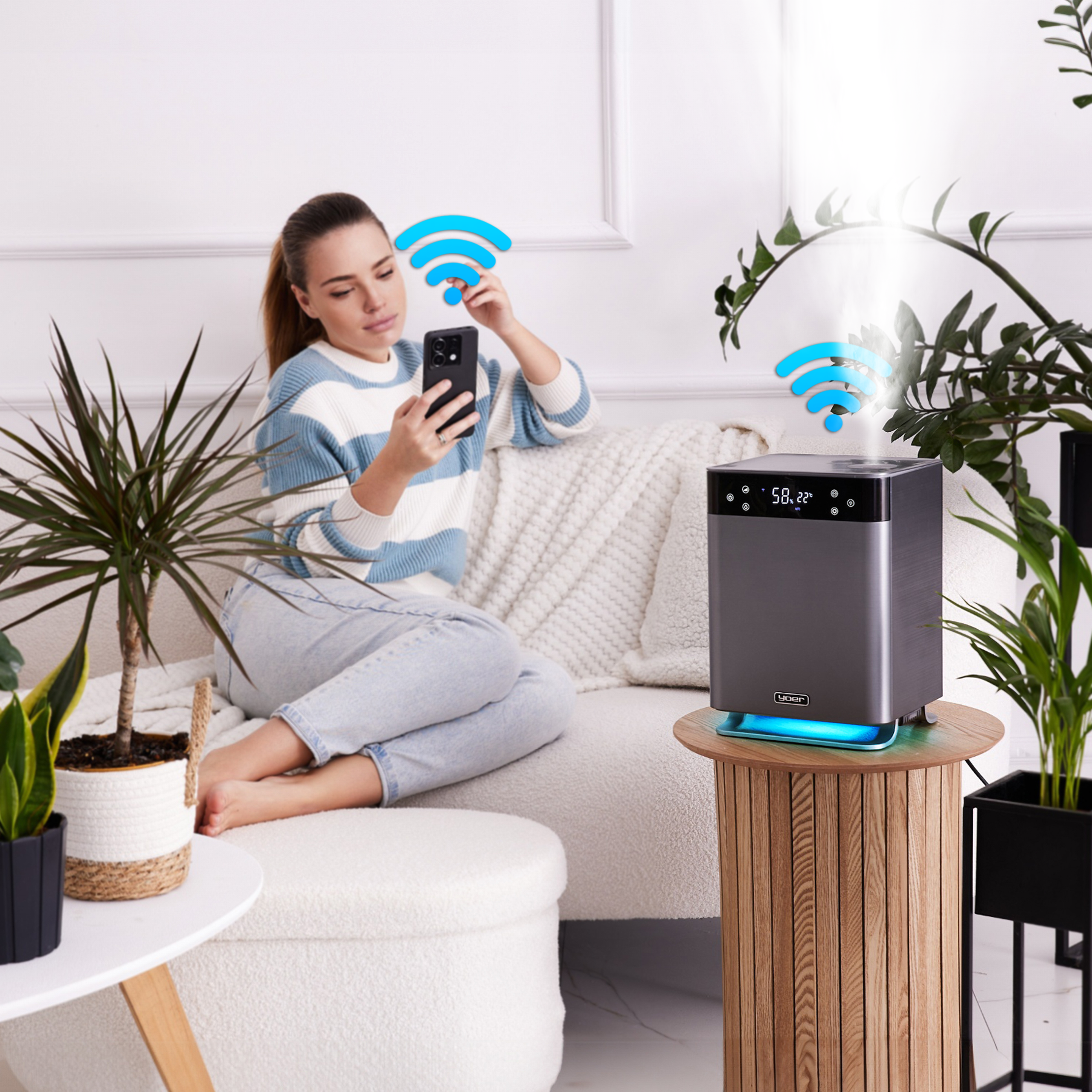 Kobieta używa telefonu w pobliżu nawilżacza, rośliny w pokoju. Obecne symbole Wi-Fi. Scena jest w pomieszczeniu.