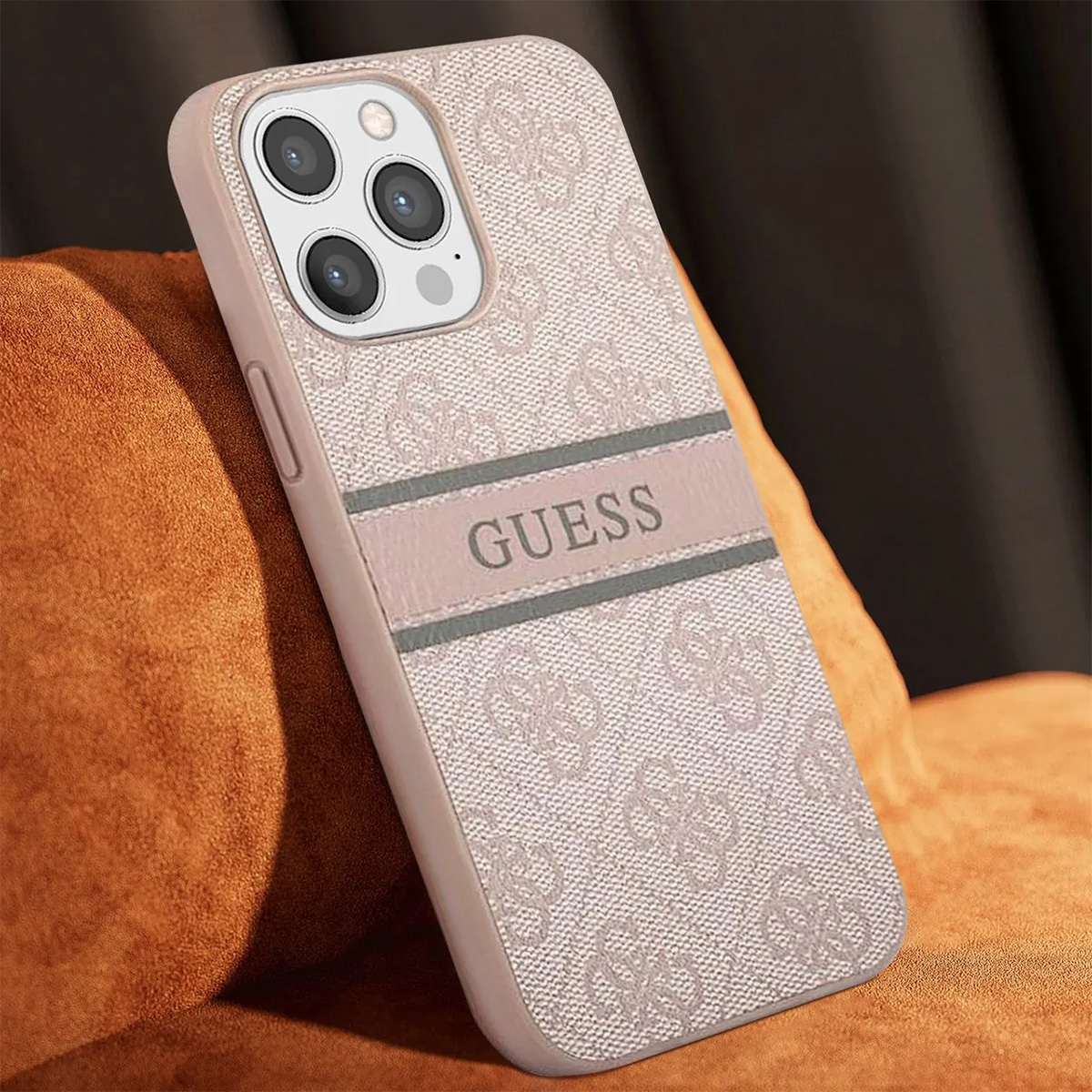 Primo piano di una custodia per telefono con il logo Guess. La custodia è rosa e ha un design a motivi. Il telefono è appoggiato su una superficie marrone.