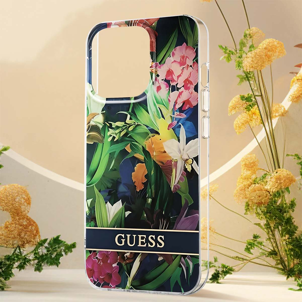 Una custodia per telefono con un design floreale e la scritta 'GUESS'. Lo sfondo presenta fiori gialli e un colore marrone chiaro.