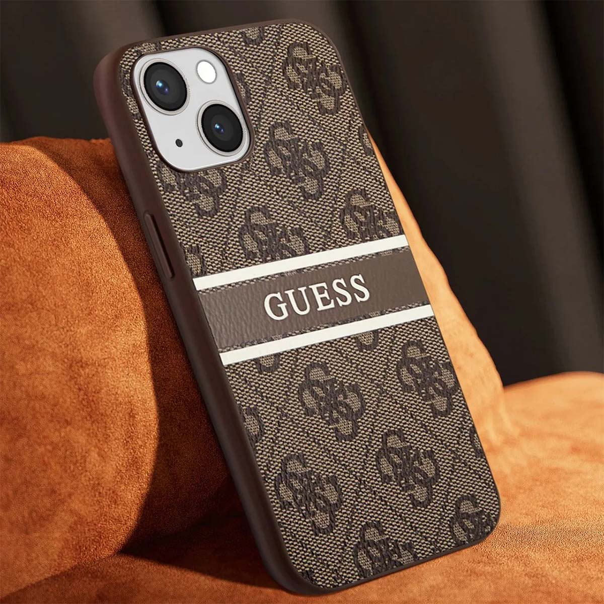 Una custodia per telefono Guess marrone con motivo logo e striscia bianca. È appoggiata su una superficie marrone.