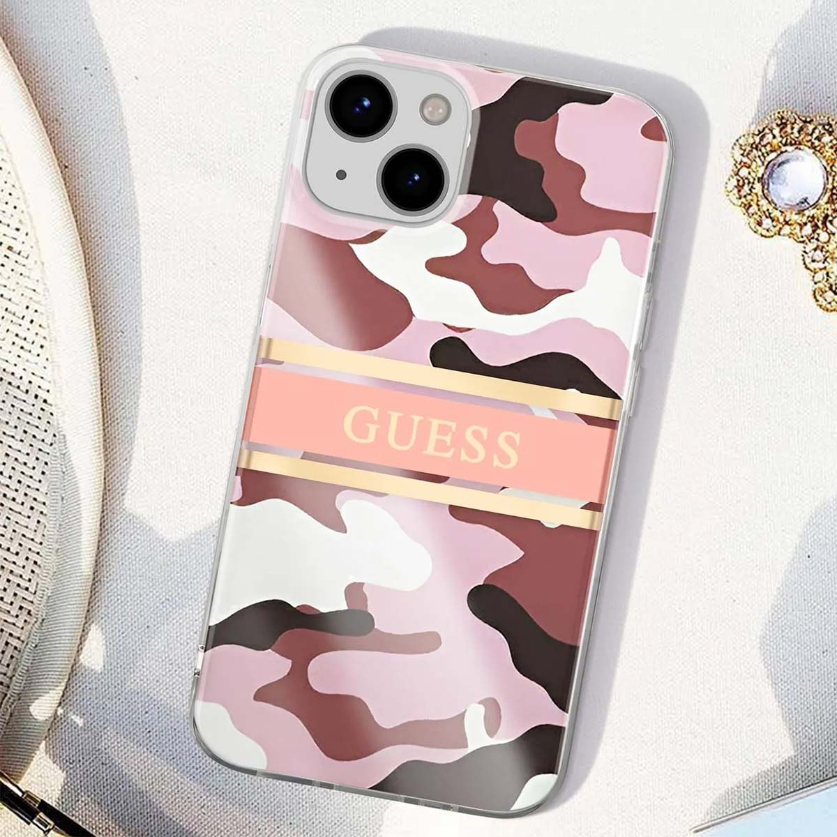 Una custodia per telefono con un motivo mimetico rosa e marrone. C'è la scritta 'GUESS'. Lo sfondo è bianco.
