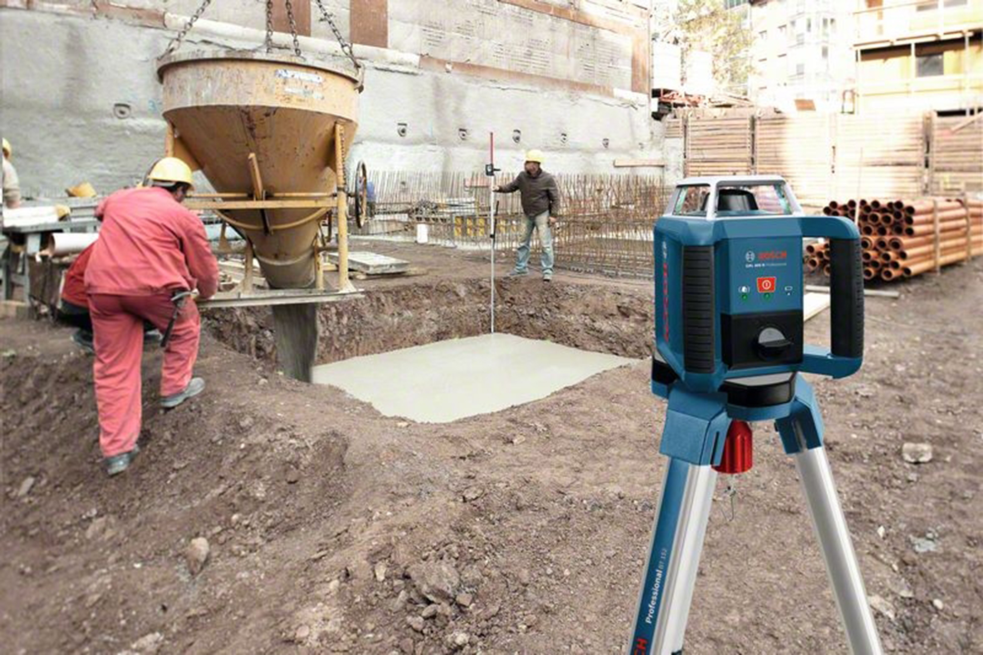 İnşaat işçileri, beton dökülüyor. Lazer seviyesi kuruldu. Çimento karıştırıcı beton kare üzerinde asılı.
