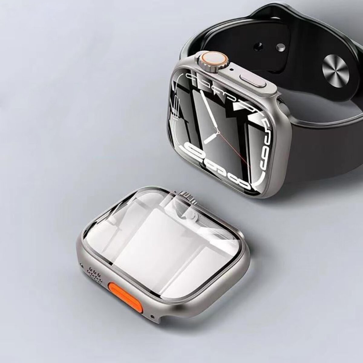 Une montre connectée grise avec un bracelet noir et un protecteur d'écran est sur une surface grise. Le protecteur est détaché.