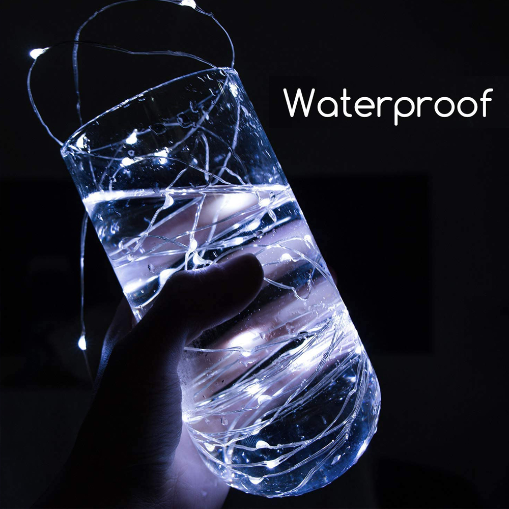 Hand hält ein Glas mit Wasser und Lichterketten. Text "Waterproof" auf der rechten Seite. Dunkler Hintergrund.