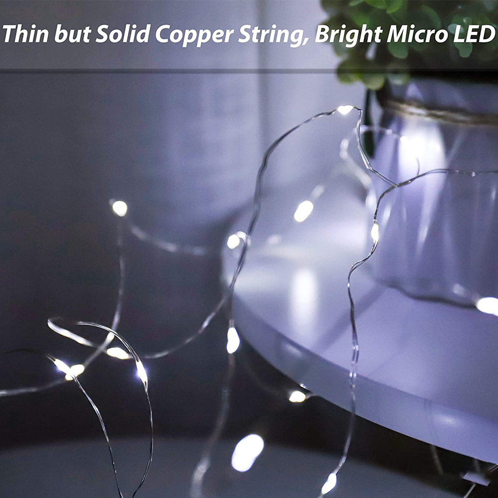 Nahaufnahme von Lichterketten. Dünner Kupferdraht mit hellen Mikro-LEDs. Im Hintergrund eine Vase. Die Szene ist weich und verträumt.