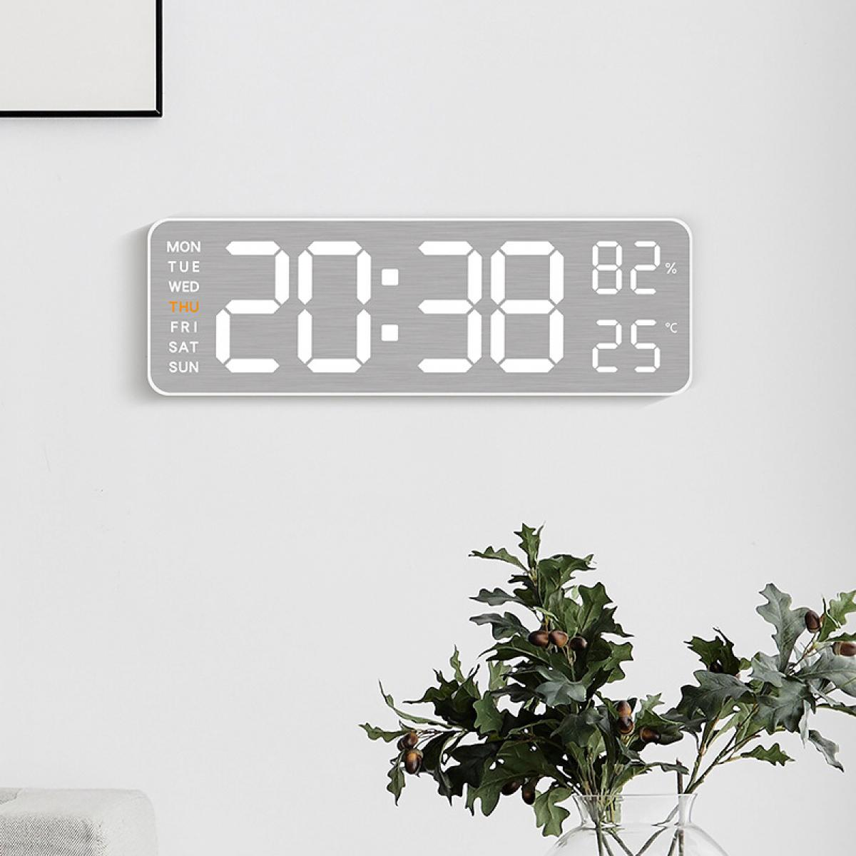Eine Digitaluhr zeigt 20:38, 82 % Luftfeuchtigkeit und 25 °C an. Der Tag ist Donnerstag. Darunter eine Pflanze in einer Vase.