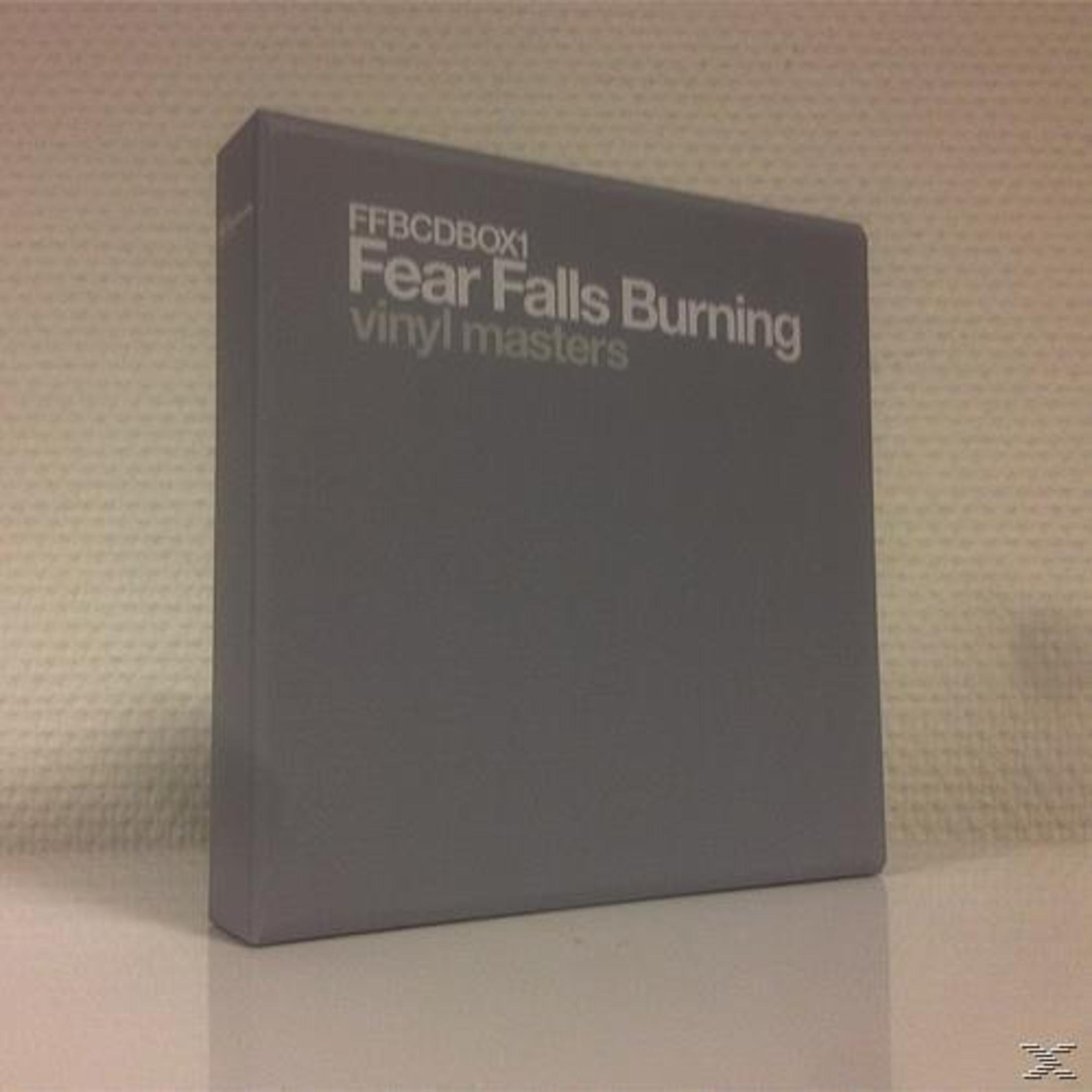 A gray CD box with text 'Fear Falls Burning' on a white surface. The background is a white textured wall.