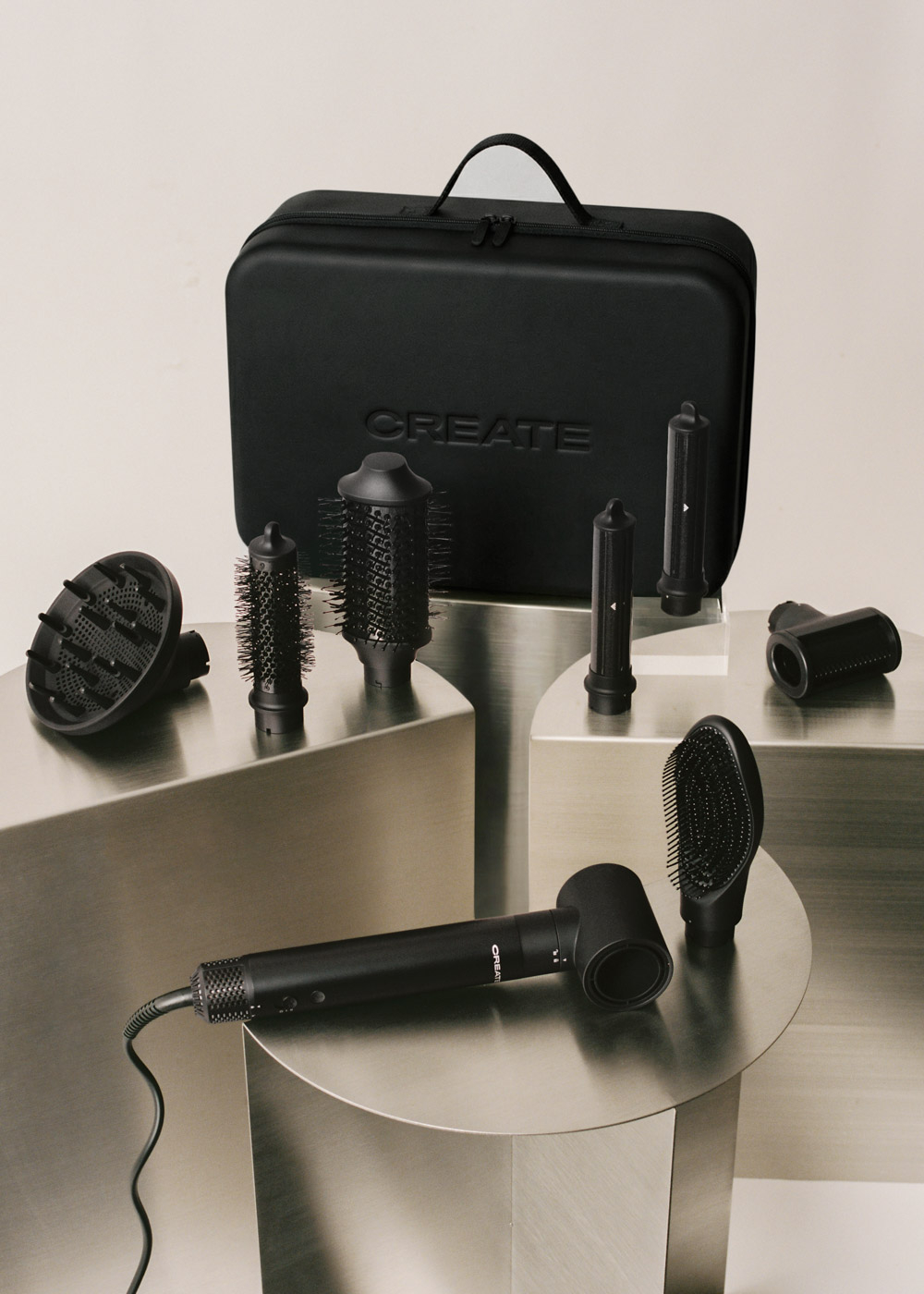 Un kit de peinado negro con varios accesorios y un estuche, colocado sobre soportes metálicos. La marca CREATE es visible.