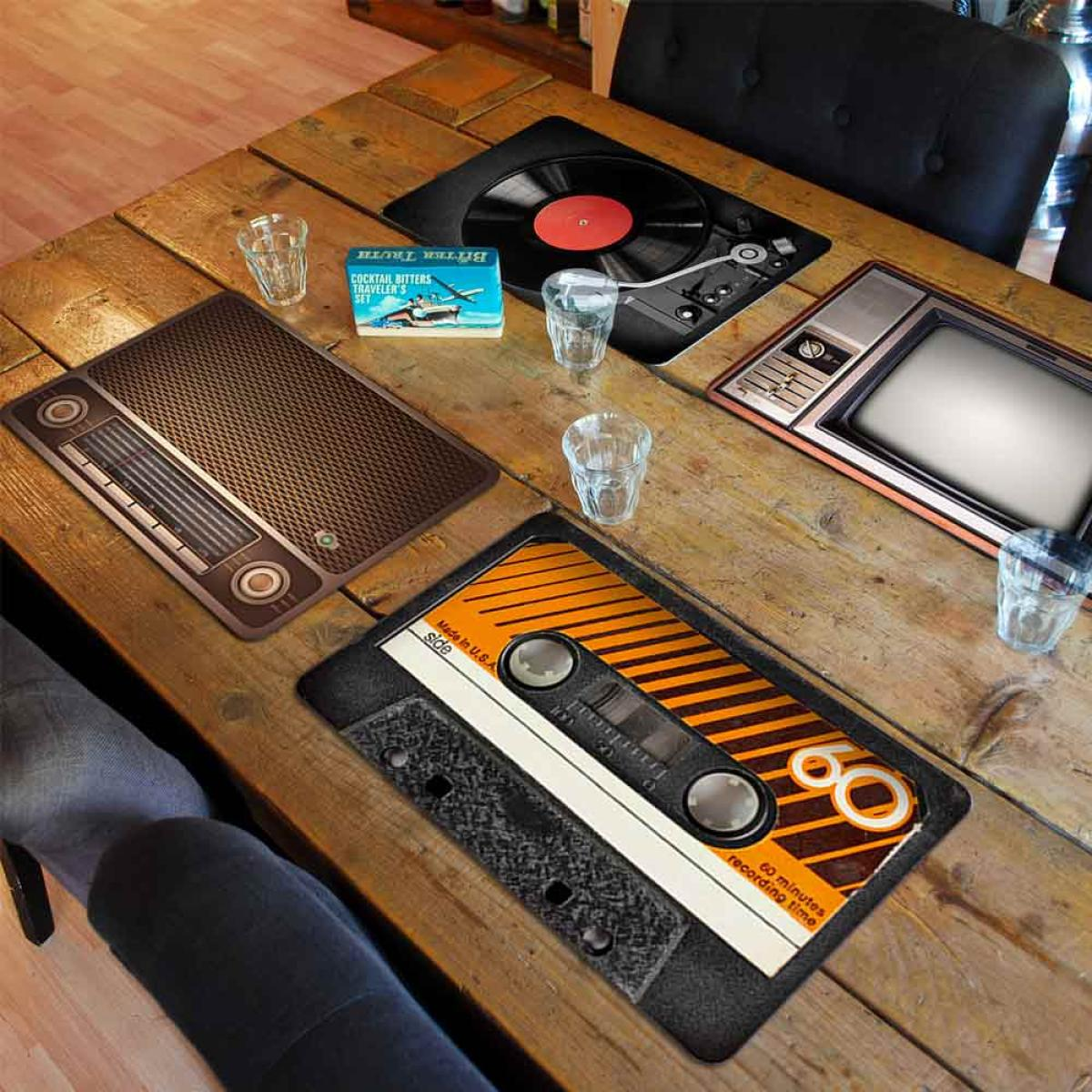 Houten tafel met retro onderzetters: radio, platenspeler, tv, cassettebandje. Glazen en een Bitter Truth doos zijn aanwezig.
