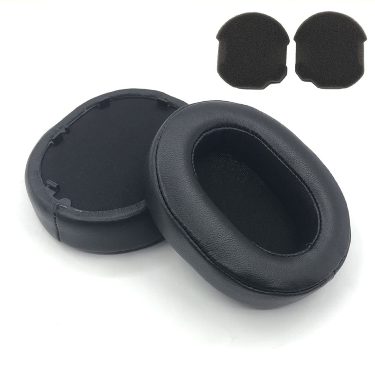 Zwei schwarze Kopfhörer-Ohrpolster und zwei kleine schwarze Schaumstoffpads liegen auf einer weißen Oberfläche.