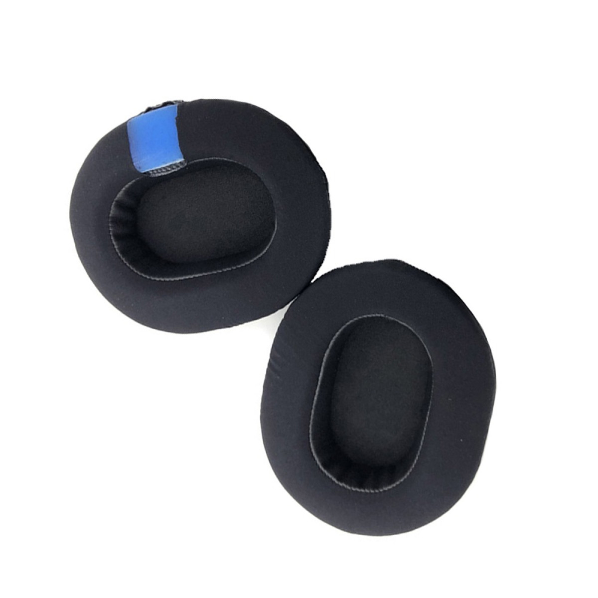 Two black ear pads for headphones, one with a blue patch, lie on a white surface. The pads have oval inner holes.
