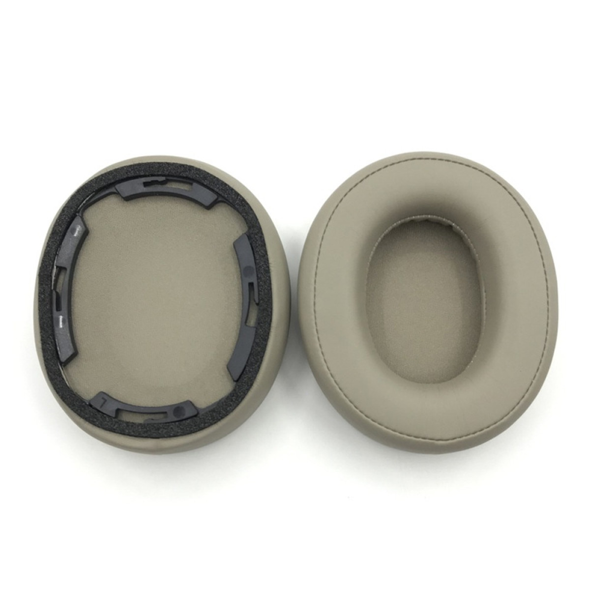 Due padiglioni auricolari beige su sfondo bianco. Uno ha un telaio interno nero, l'altro è liscio. Entrambi hanno fori centrali.