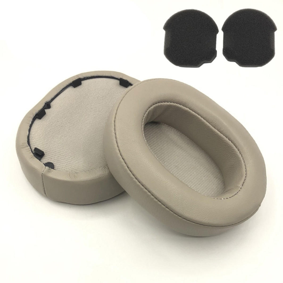 Kopfhörer-Ohrpolster und Schaumstoffstücke. Beige Ohrpolster, eines mit freiliegendem Innenraum. Zwei schwarze Schaumstoffstücke oben.