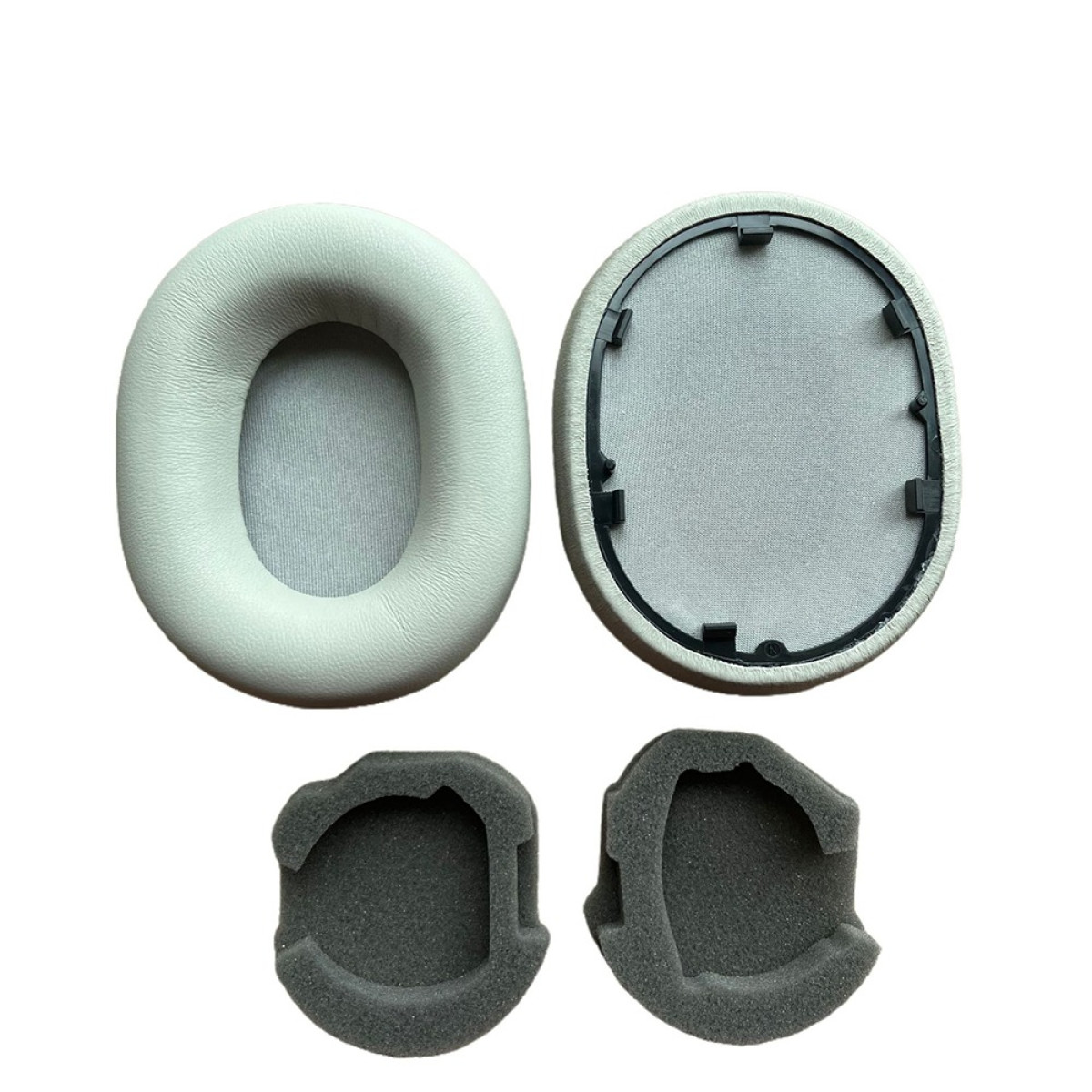 Quattro parti di cuffie: due cuscinetti auricolari grigio chiaro, uno con cornice nera e due inserti in schiuma grigio scuro, il tutto su sfondo bianco.