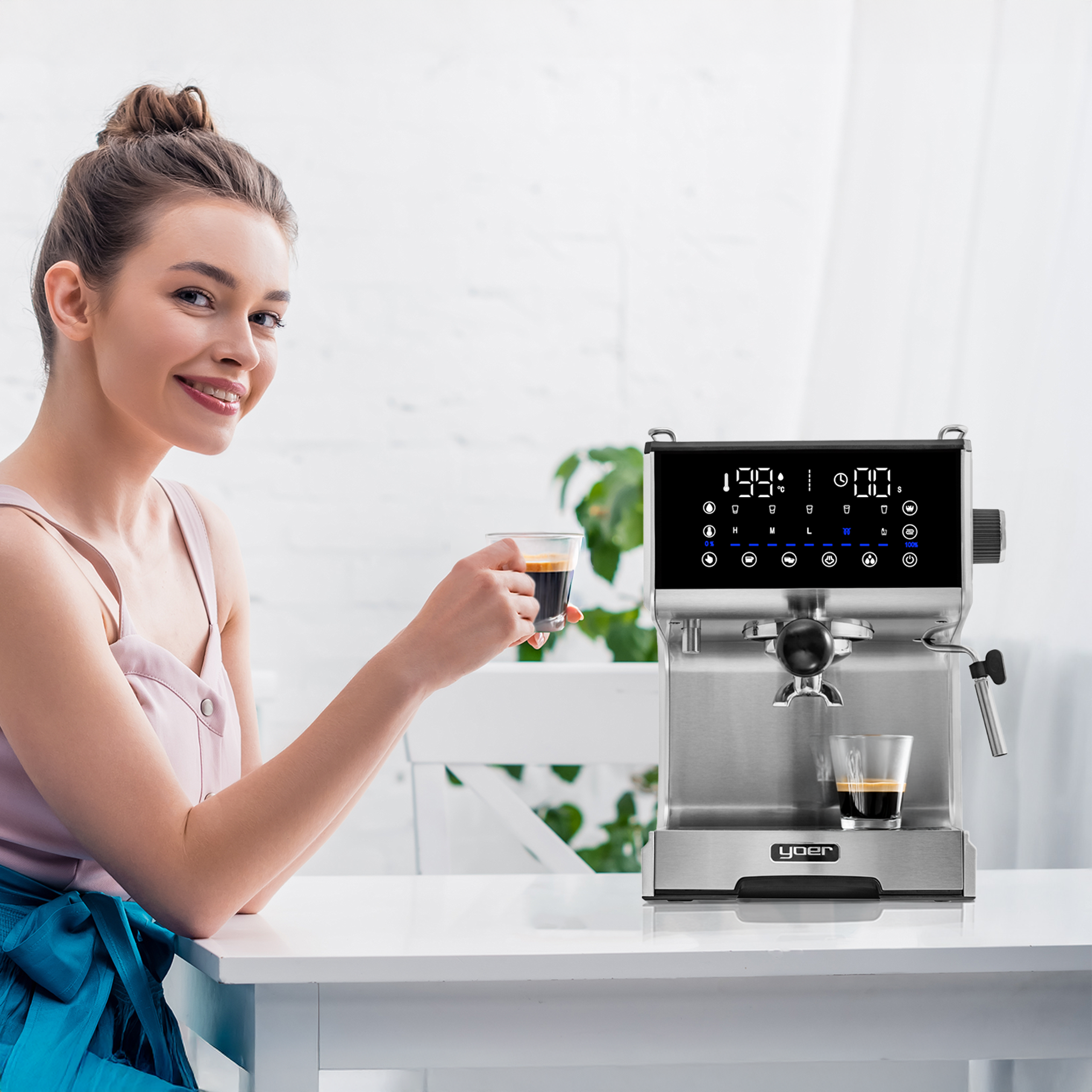 Kobieta uśmiecha się, trzymając kawę w pobliżu ekspresu do kawy. Scena jest jasna i we wnętrzu.